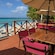 Two tables with chairs and umbrellas on a beachfront deck